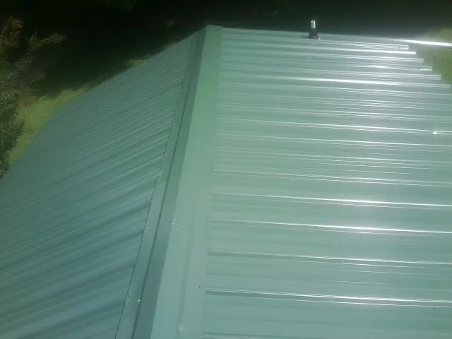 New green metal panels meeting at the ridge of a roof — Flat Roof Repair work by our crew in Turon
