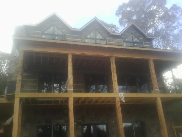Dormers and porch framing on a large log home under construction — Roof Coating work by our crew in Turon