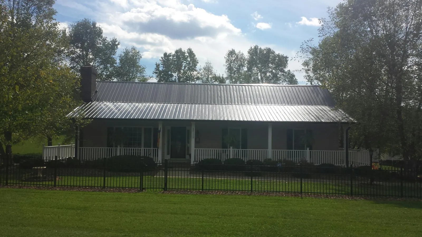 Gray metal roof on a brick ranch with a full width front porch — Gutter Guard Installation work by our crew in Turon