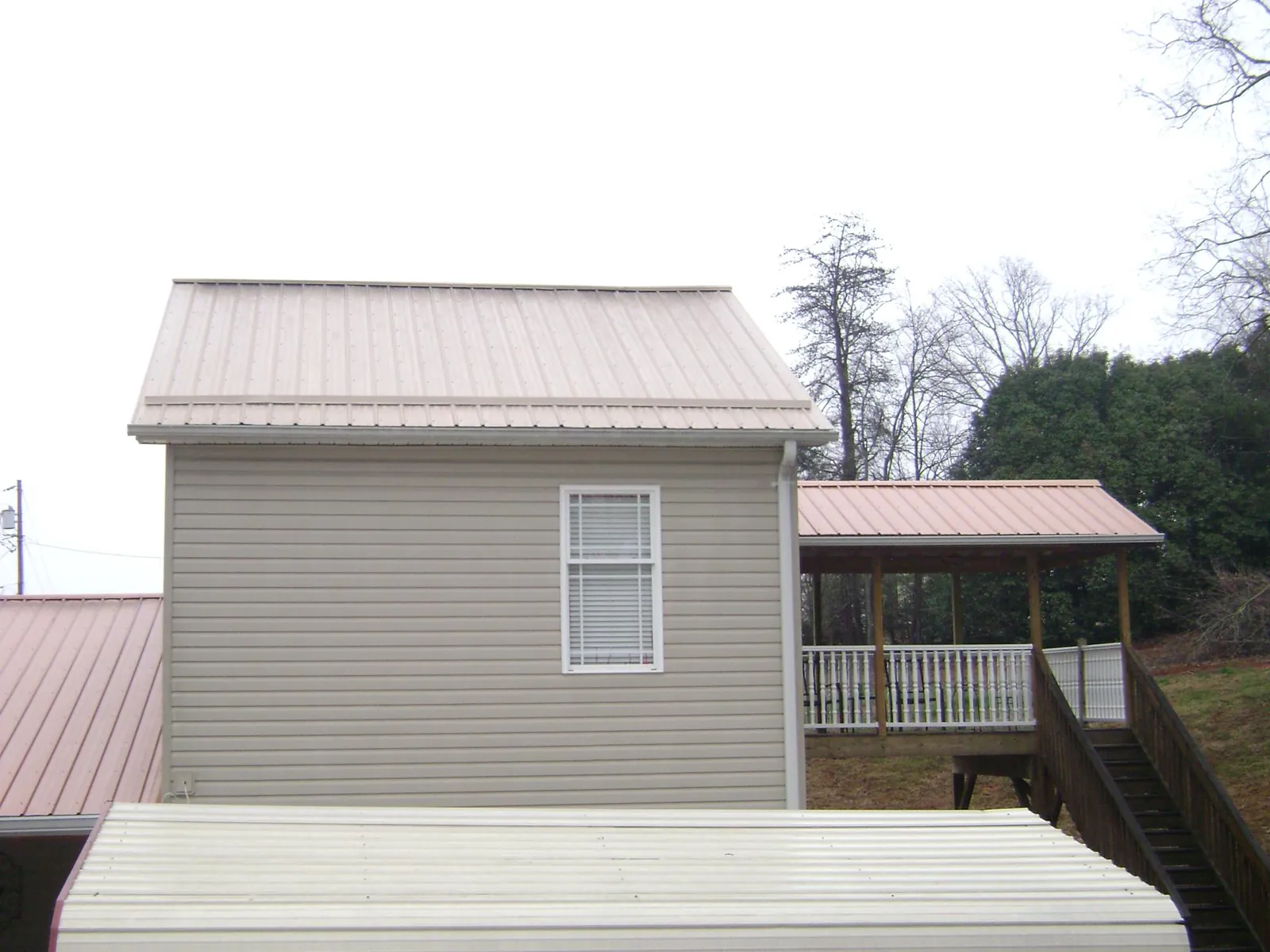 Tan metal roofs on a two story addition and attached porch, from a Roof Replacement job in Turon