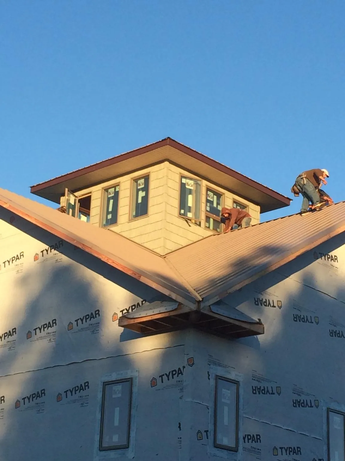 Roofers working around a rooftop cupola on a new metal roof at sunset — Roof Waterproofing in Turon by Roofing Brothers